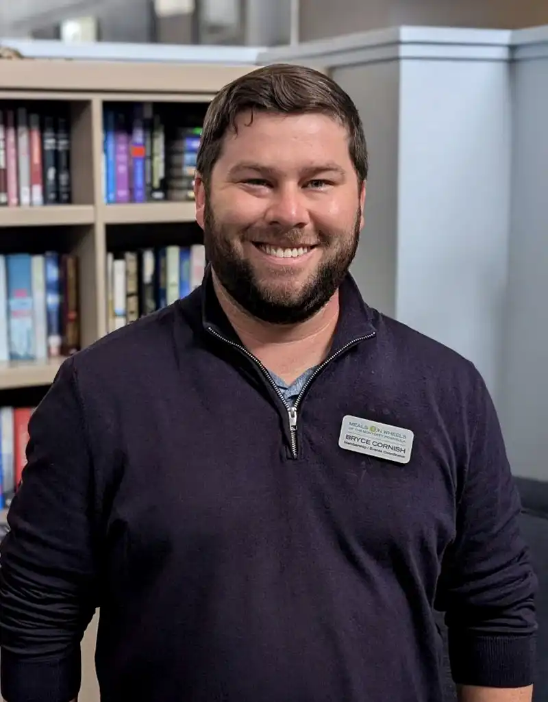 Operations Assistant Manager Bryce Cornish smiling in an office setting at Meals on Wheels of the Monterey Peninsula.