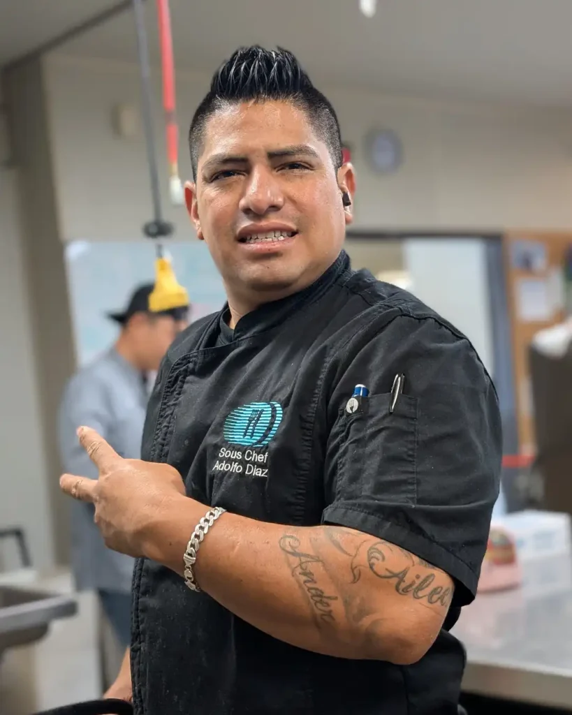 Portrait of Adolfo Diaz, Executive Sous Chef at Meals on Wheels of the Monterey Peninsula, wearing professional kitchen attire.