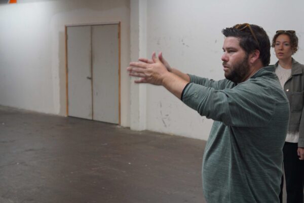 Meals on Wheels of the Monterey Peninsula team members standing inside the purchased building during a site visit, discussing use of an open interior space.